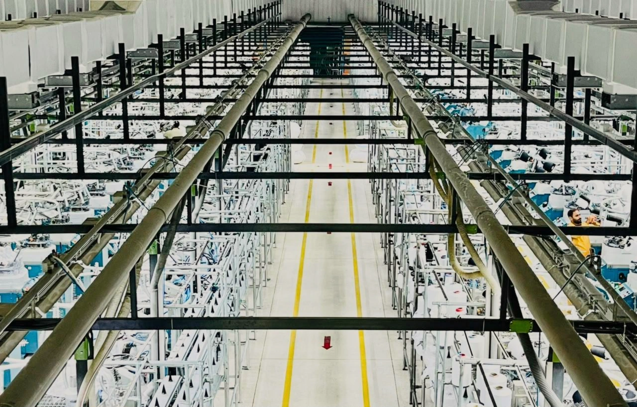 Overhead view of a circular knitting hall with symmetrical production aisles and machinery lines.